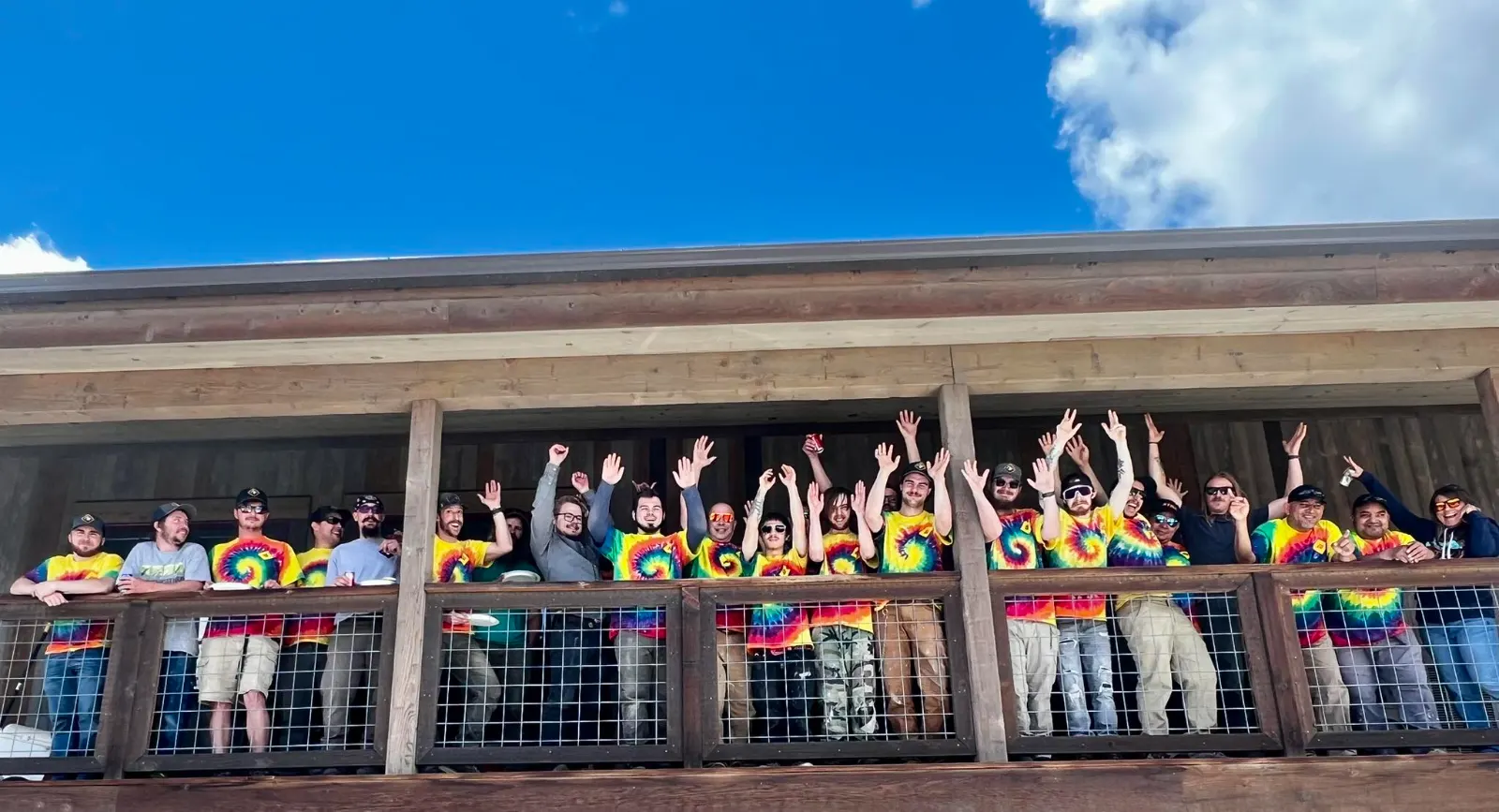 The Rocky Mountain Catastrophe team in matching tie-dye shirts cheering on the office balcony